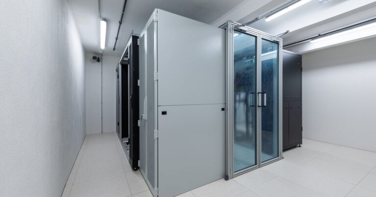 A cold aisle containment unit for a data center with a transparent door inside a bright and sterile white room.