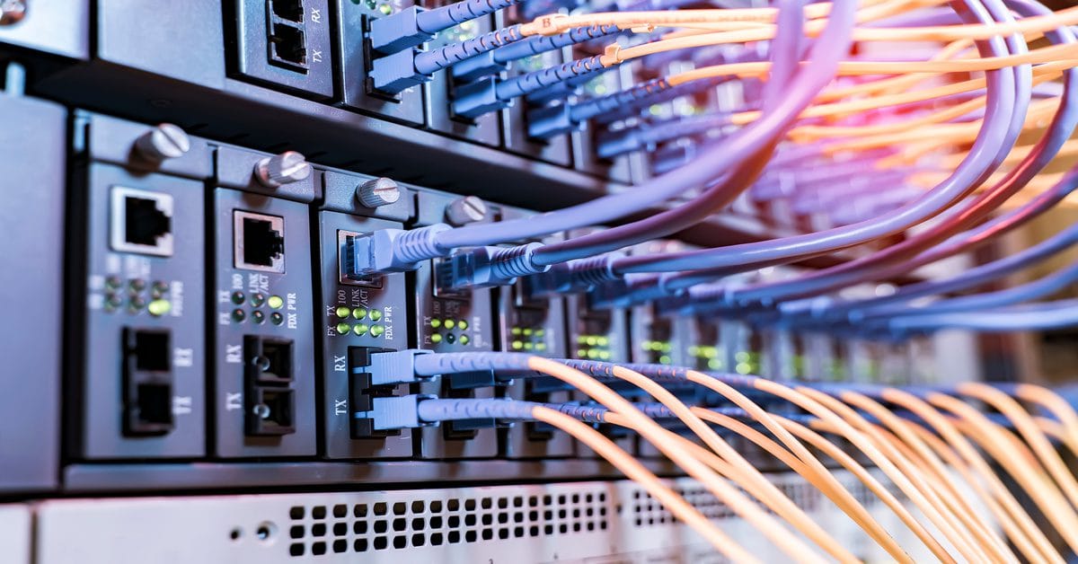 A close-up of many blue-and-orange fiber optic cables plugged into a server for high speed data transmission.